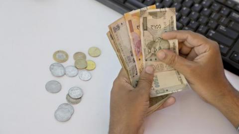 Man counting Indian rupees & coins